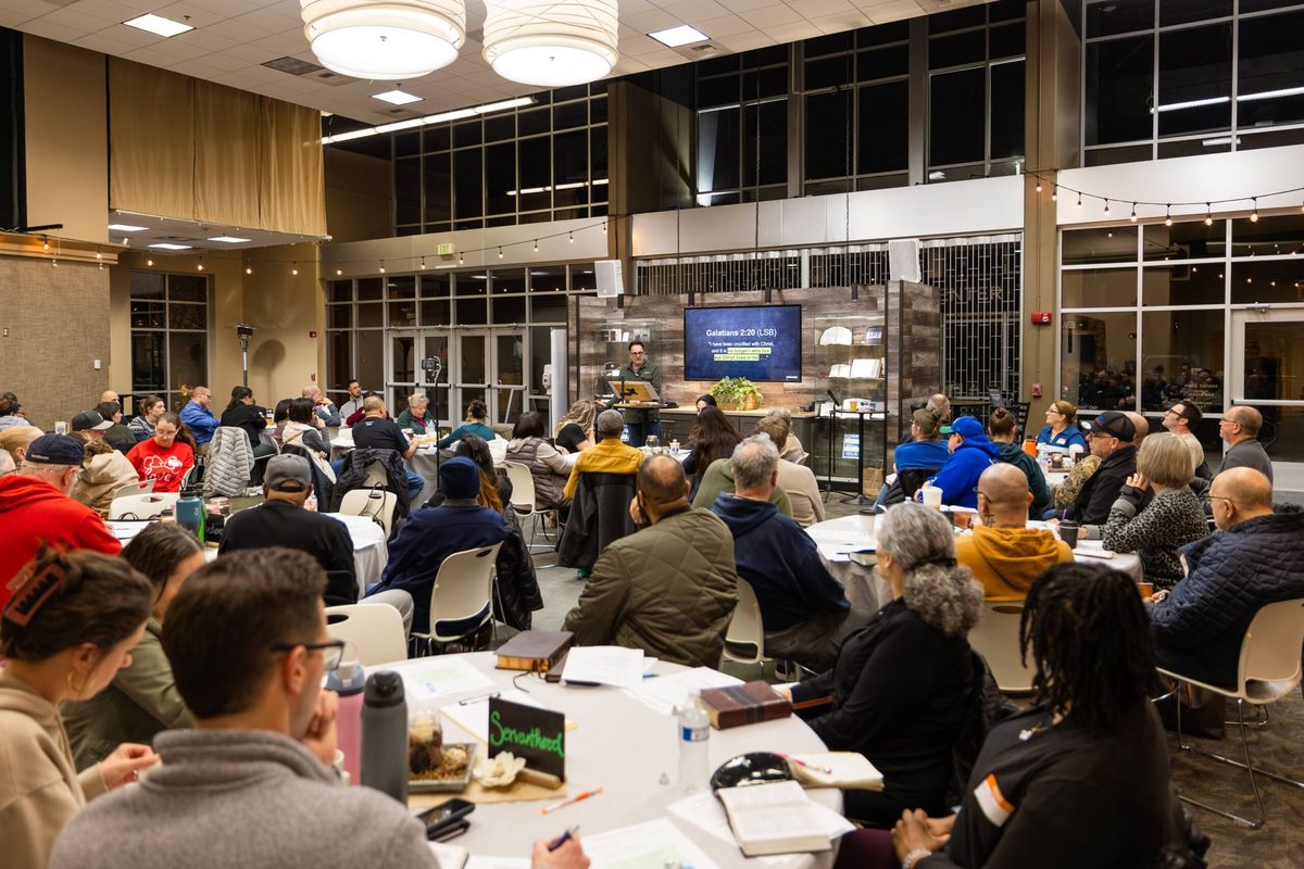 A full room gathered at round tables for a church-wide Bible study