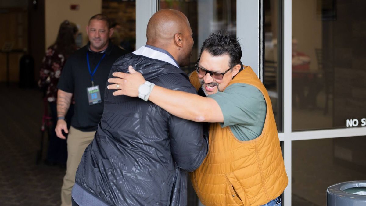 Two men share a warm hug in the church lobby on a Sunday morning