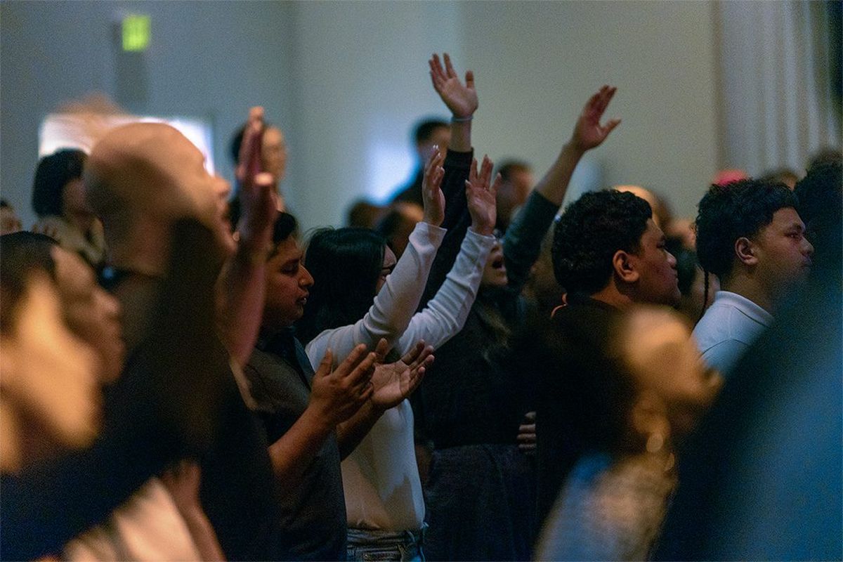 People in the congregation with hands raised in worship