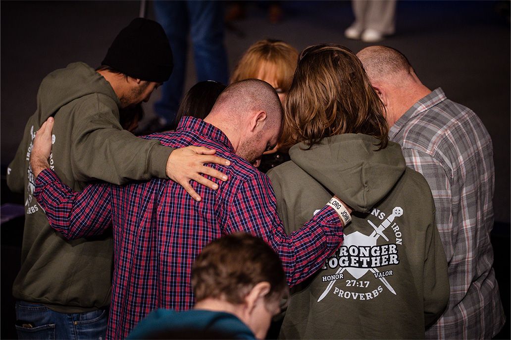 Men gather close and pray together